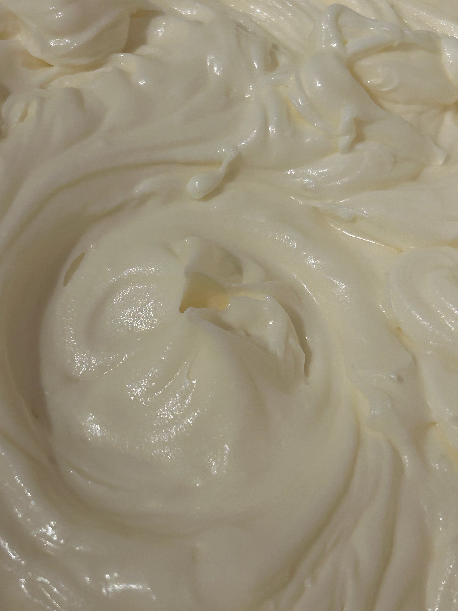 Close-up of creamy white whipped body butter with a swirl pattern